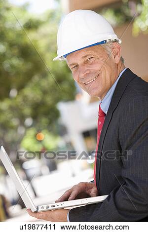 Middle-aged surveyor using laptop outdoors, portrait View Large Photo Image Stock Image - Middle-aged surveyor using laptop outdoors, portrait. Fotosearch