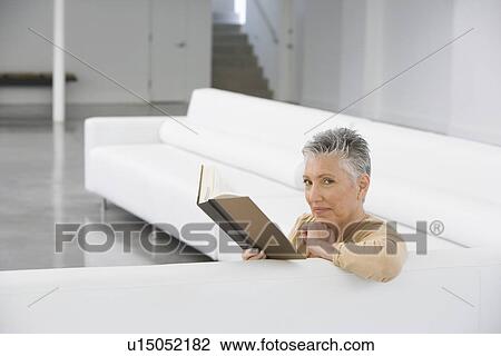 Middle-aged woman reading book on sofa View Large Photo Image Stock Image - Middle-aged woman reading book on sofa. Fotosearch