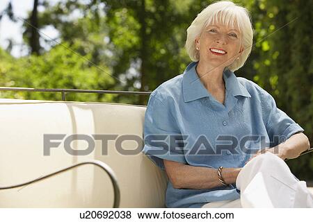 Stock Photo - Middle-aged Woman Sitting on sofa in back yard. Fotosearch