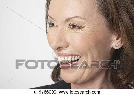 Stock Image - Middle-aged woman smiling big, side view, close-up. Fotosearch