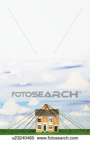 Stock Photography - Model house tied down with string. Fotosearch