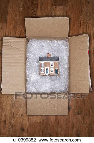 Stock Image - Model of house on bubble wrap in packing carton, view from above. Fotosearch