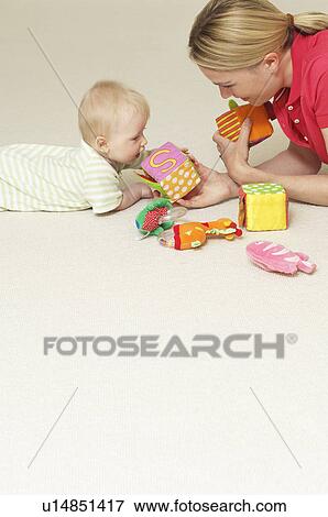 Stock Photo - Mother and child playing with toys on floor. Fotosearch