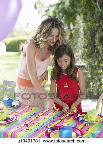 Stock Image - Mother and daughter (7-9) laying table for birthday party. Fotosearch