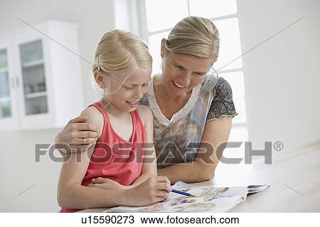 Stock Image - Mother and Daughter Colouring in book at kitchen table. Fotosearch