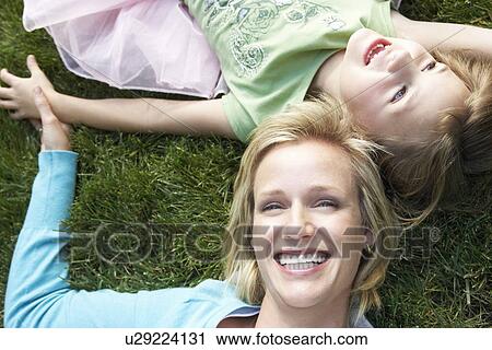 Stock Image - Mother and daughter lying on grass, view from above. Fotosearch