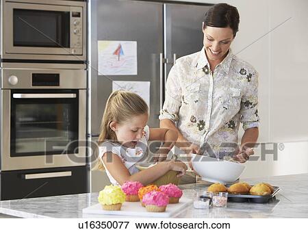 Stock Photo - Mother and Daughter Making Cupcakes in kitchen. Fotosearch