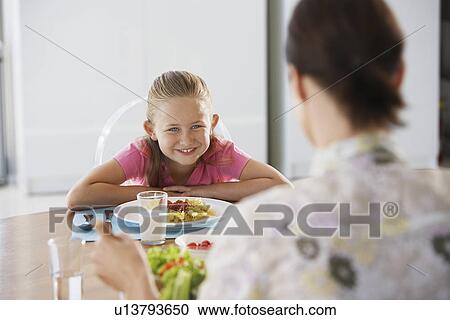 Mother and daughter sitting at table eating pasta View Large Photo Image Stock Image - Mother and daughter sitting at table eating pasta. Fotosearch