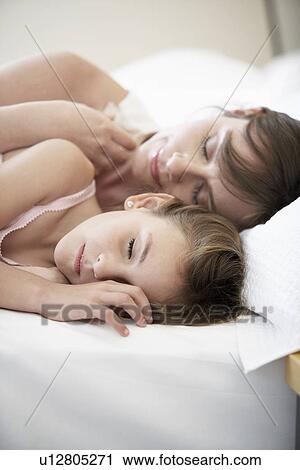 Stock Image - Mother and daughter sleeping in bed, portrait. Fotosearch
