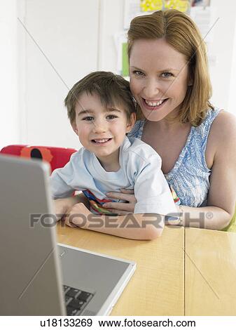 Stock Photo - Mother and son (3-6) using laptop, indoors, (portrait). Fotosearch