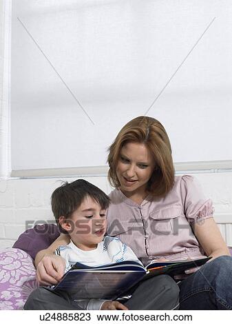 Mother and son (5-6) reading book on couch in living room View Large Photo Image Stock Image - Mother and son (5-6) reading book on couch in living room. Fotosearch