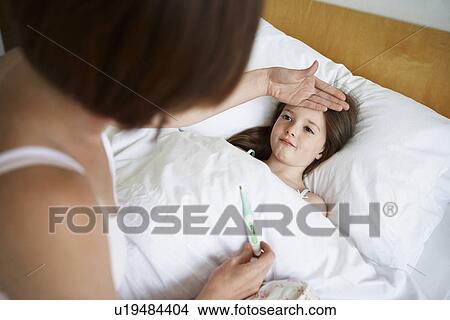 Picture - Mother checking temperature of daughter in bed. Fotosearch