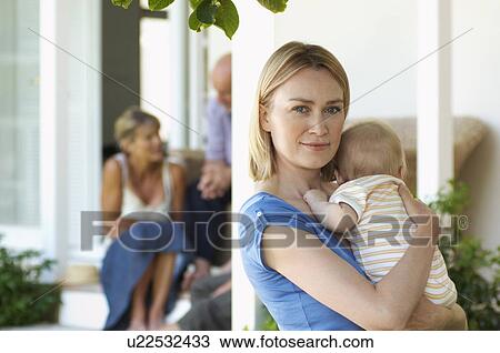 Stock Image - Mother holding baby on porch with grandparents behind. Fotosearch