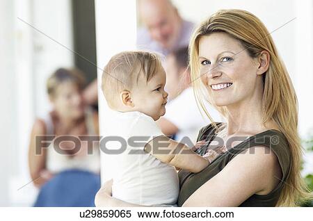 Stock Photography - Mother holding baby on porch with grandparents behind. Fotosearch