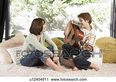 Mother listening to son play guitar View Large Photo Image Stock Image - Mother listening to son play guitar. Fotosearch