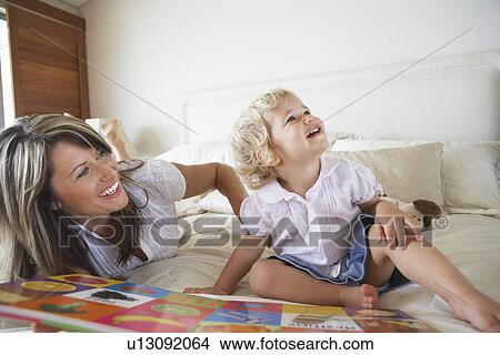 Mother lying on stomach on bed, Playing with Son View Large Photo Image Picture - Mother lying on stomach on bed, Playing with Son. Fotosearch