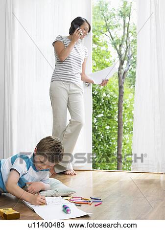 Mother using cell phone, young son drawing on floor View Large Photo Image Stock Image - Mother using cell phone, young son drawing on floor. Fotosearch