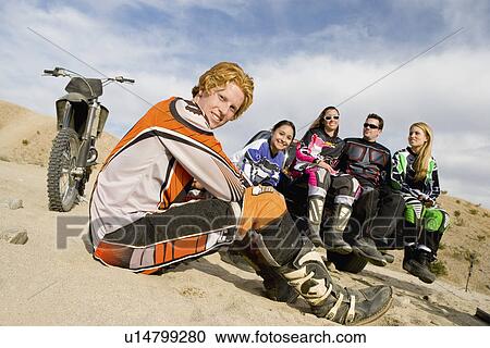 Stock Image - Motocross racers in desert, (portrait). Fotosearch