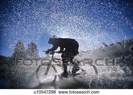 Stock Photo - Mountain Bicyclist Splashing Through Water, side view. Fotosearch