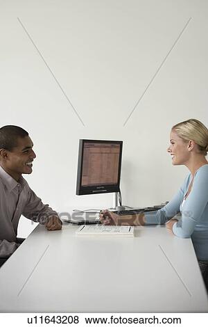Office worker and client sitting at desk, side view View Large Photo Image Stock Photo - Office worker and client sitting at desk, side view. Fotosearch
