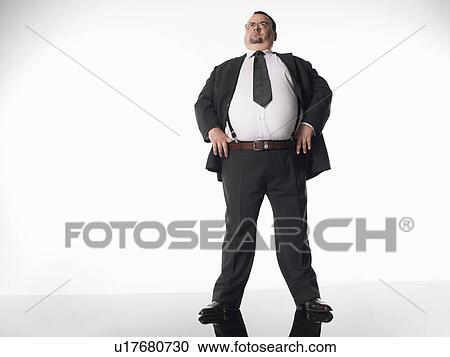 Overweight businessman standing with thumbs in belt View Large Photo Image Stock Image - Overweight businessman standing with thumbs in belt. Fotosearch