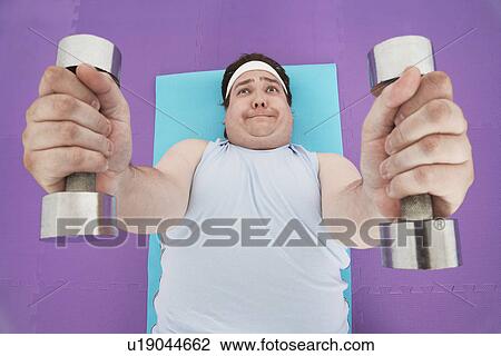 Overweight Man lying down Lifting dumbbells, overhead view View Large Photo Image Stock Image - Overweight Man lying down Lifting dumbbells, overhead view. Fotosearch