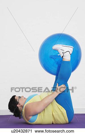 Overweight Woman lying down lifting exercise ball with legs View Large Photo Image Stock Image - Overweight Woman lying down lifting exercise ball with legs. Fotosearch