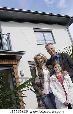 Parents and daughter (7-9) embracing outside new home, portrait View Large Photo Image Stock Photo - Parents and daughter (7-9) embracing outside new home, portrait. Fotosearch