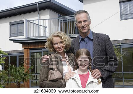 Parents and daughter (7-9) embracing outside new home, portrait View Large Photo Image Stock Photo - Parents and daughter (7-9) embracing outside new home, portrait. Fotosearch
