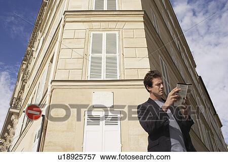 Paris, France, Man studying guide book in front of apartment block View Large Photo Image Stock Photo - Paris, France, Man studying guide book in front of apartment block. Fotosearch