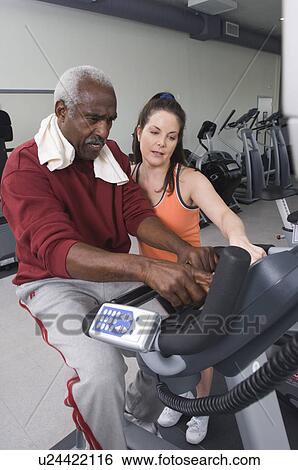 Stock Photograph - Personal Trainer Working with Senior Man. Fotosearch