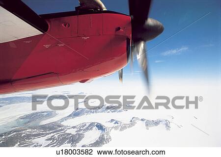 Stock Image - Plane Flying over Snowy Landscape, cropped. Fotosearch