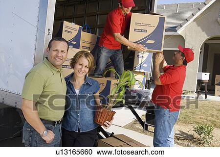 Stock Image - Portrait of couple and workers unloading truck. Fotosearch