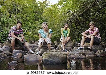 Portrait of four teenagers (16-17 years) sitting on stones by river View Large Photo Image Stock Photo - Portrait of four teenagers (16-17 years) sitting on stones by river. Fotosearch