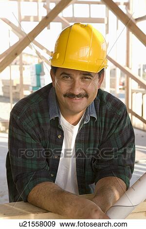 Stock Photo - Portrait of man at construction site in hardhat. Fotosearch