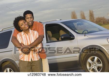 Portrait of mid-adult couplein front of car View Large Photo Image Stock Photo - Portrait of mid-adult couplein front of car. Fotosearch