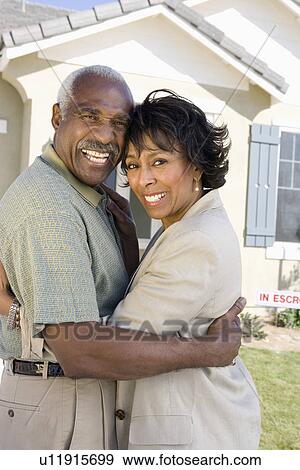 Stock Photo - Portrait of middle-aged couple hugging and smiling, outdoors. Fotosearch