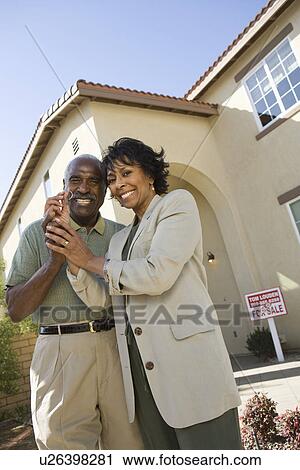 Stock Image - Portrait of middle-aged couple with key to new home. Fotosearch