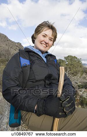 Stock Photo - Portrait of middle-aged woman holding hiking pole and smiling. Fotosearch