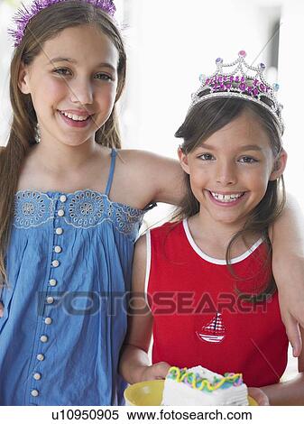 Stock Photography - Portrait of two girls (7-9, 10-12) in tiaras, smiling. Fotosearch