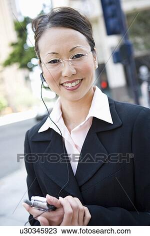 Stock Image - Portrait of young businesswoman with mobile and bluetooth. Fotosearch