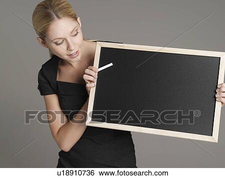 Stock Photograph - Portrait of young female teacher holding blackboard. Fotosearch