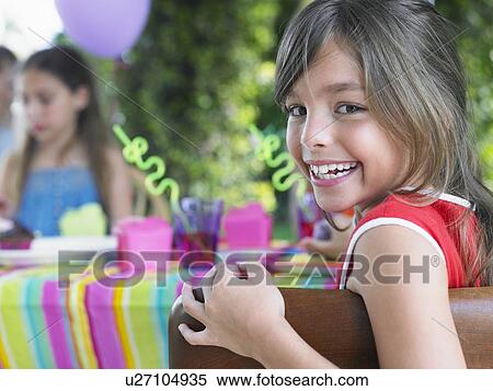 Stock Photography - Portrait of young girl (10-12) at birthday party, looking over shoulder. Fotosearch
