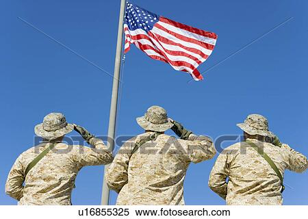 Rear view of three U. S military personnel saluting the American flag against bright blue sky View Large Photo Image Stock Photography - Rear view of three U. S military personnel saluting the American flag against bright blue sky. Fotosearch