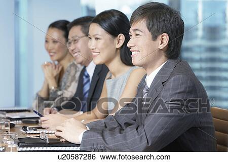 Stock Photograph - Row of business people sitting at table in conference room. Fotosearch