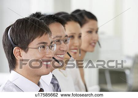 Row of customer service representatives wearing telephone headsets in office, head and shoulders View Large Photo Image Stock Image - Row of customer service representatives wearing telephone headsets in office, head and shoulders. Fotosearch