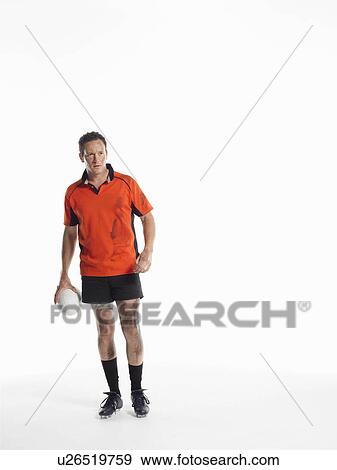 Stock Photo - Rugby player standing holding ball. Fotosearch
