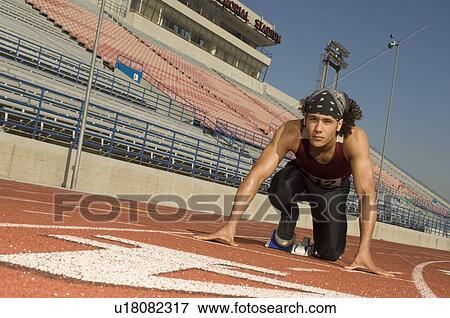 Stock Photo - Runner on a track in starting block. Fotosearch