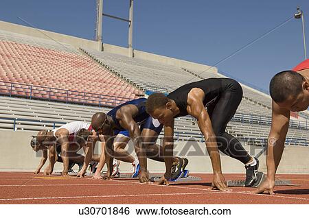 Runners waiting in starting blocks on track View Large Photo Image Stock Photograph - Runners waiting in starting blocks on track. Fotosearch
