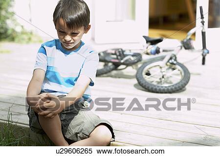 Stock Photography - Sad little boy sitting on porch of house. Fotosearch